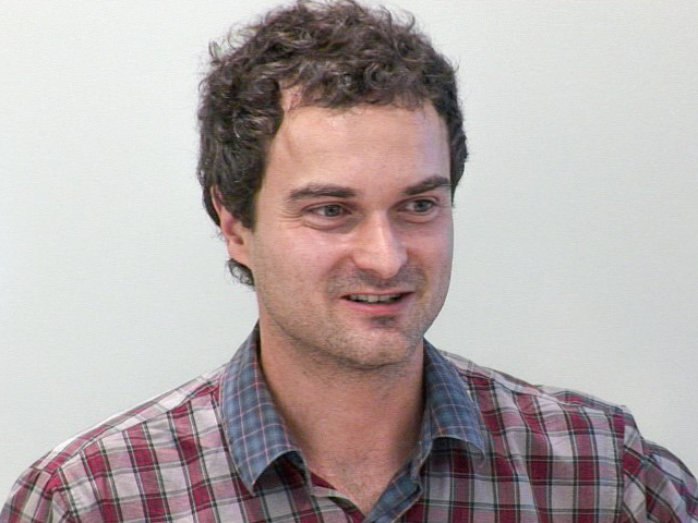 a man wearing a striped shirt and looking at the camera