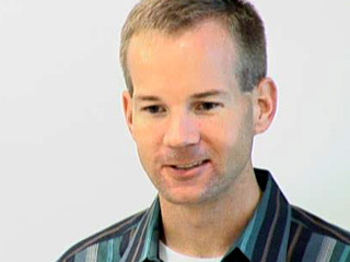 a man wearing a striped shirt and smiling at the camera