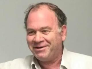 a man wearing glasses and smiling at the camera