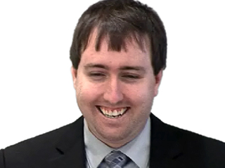 Kevin Johnson wearing a suit and tie smiling at the camera