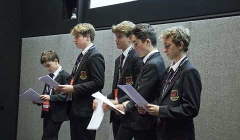 a group of people standing next to a man in a suit and tie