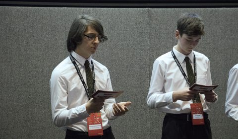 a group of people standing next to a person in a suit and tie