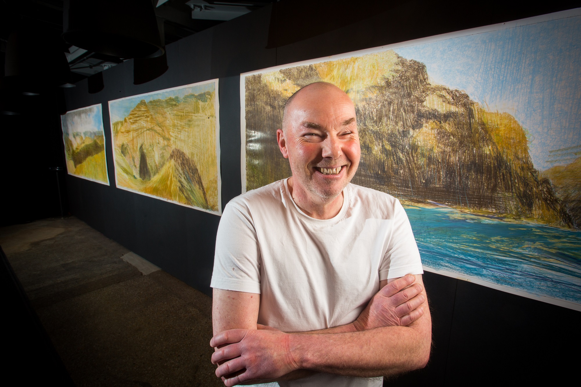 Artist Keith Salmon in front of his paintings of Hells Canyon in 