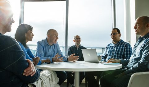 a group of people sitting at a table looking at a laptop
