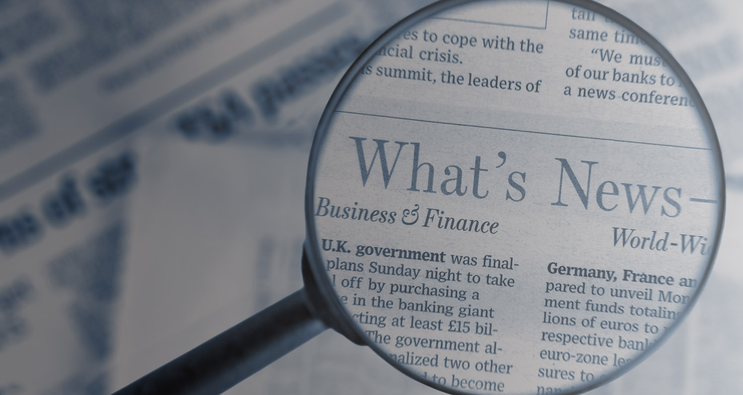 Close-up on black magnifying glass above The Wall Street Journal newspaper, blue toned.