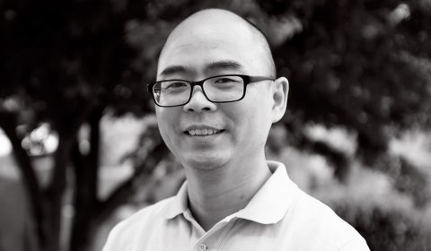 a man wearing glasses and smiling at the camera