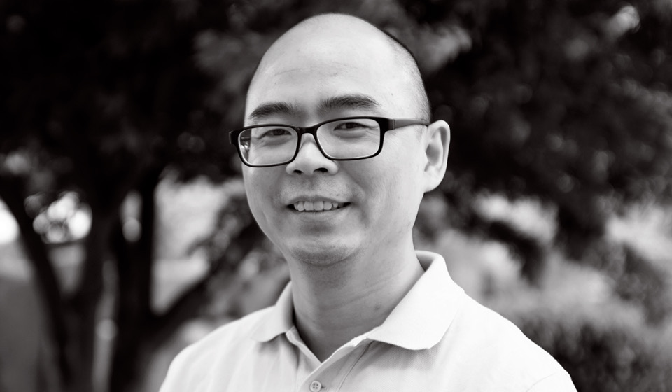 a man wearing glasses and smiling at the camera