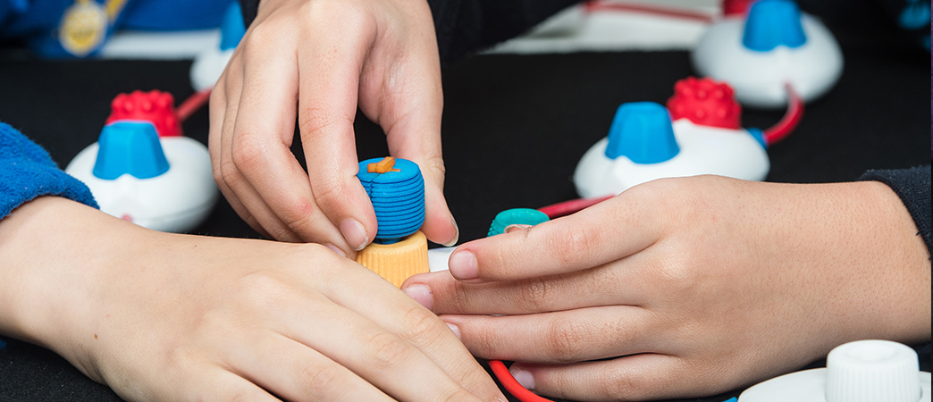 children's hands grasping a physical coding object