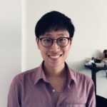 a man wearing glasses and smiling at the camera