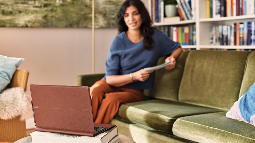 women sits on green couch looking at a tablet on the coffee table in front of her