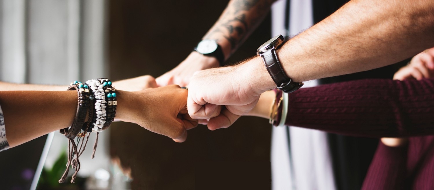 Photograph of hands joined in a circle hitting their knuckles