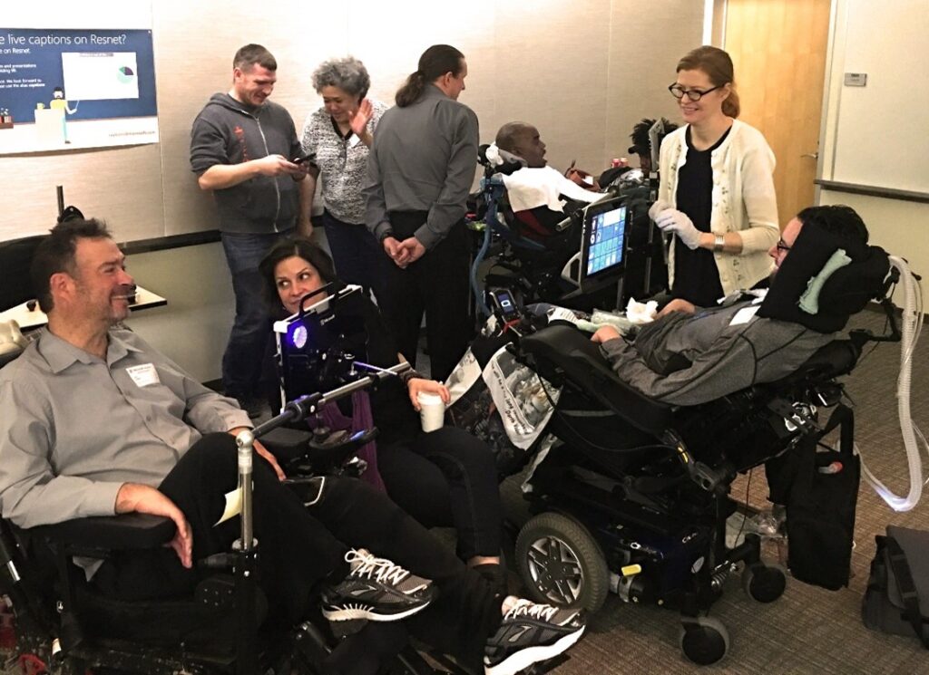 A group of people are smiling and laughing while conversing in a room. 