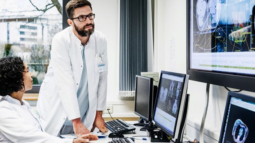 a man standing in front of a monitor displaying a health scan