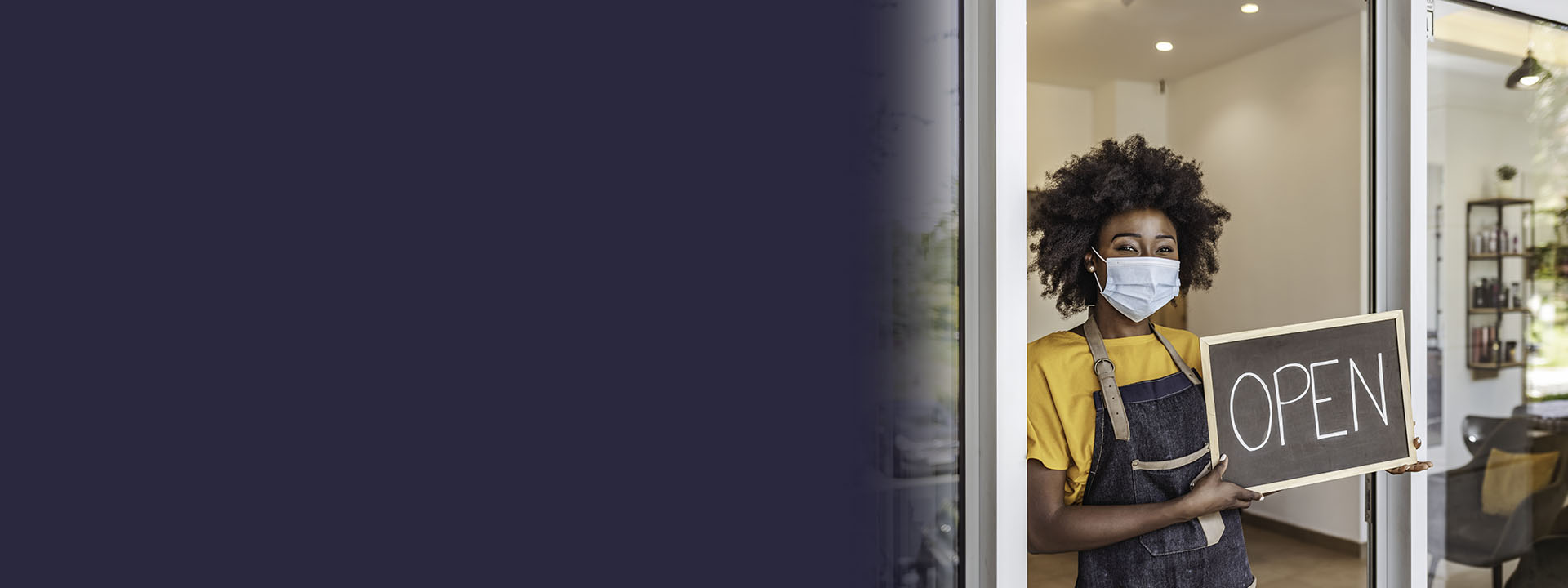 societal resilience header: woman wearing a mask holding an 'open' sign in the doorway of her store