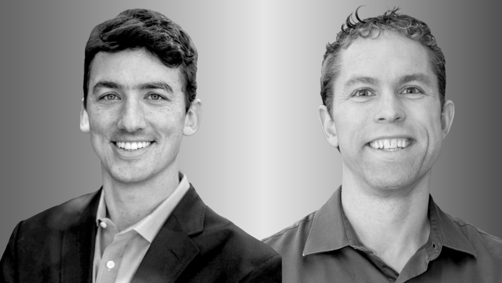 a man wearing a suit and tie smiling and looking at the camera