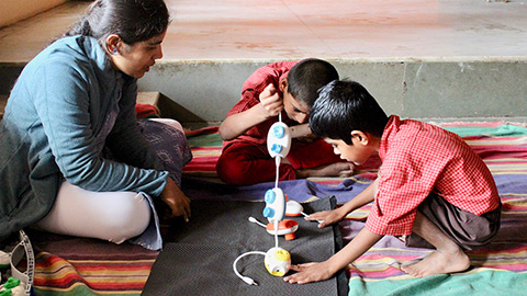 Ludic Design - woman sitting on the floor with two children working on a project