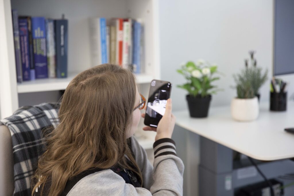 A woman holds her phone up to recognize items on a table