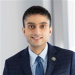 a young man wearing a suit and tie smiling at the camera