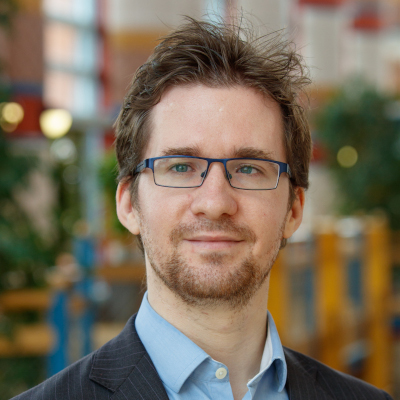 David Stillwell wearing a suit and tie smiling and looking at the camera