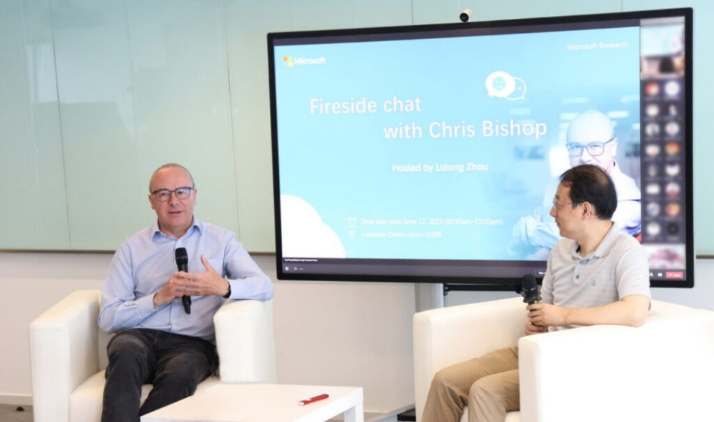Christopher Bishop et al. sitting at a table in front of a television