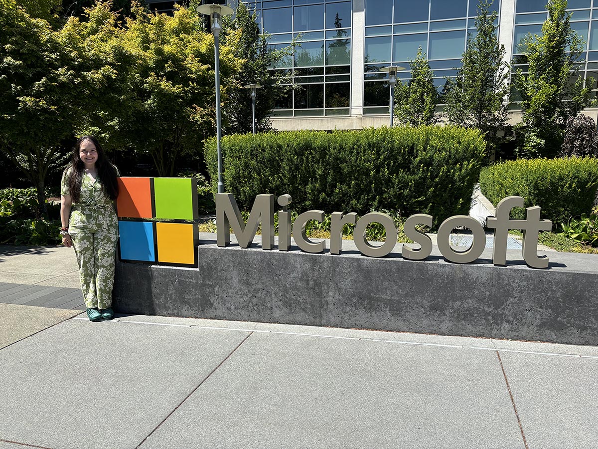 Angela Busheska standing to the left of the Microsoft sign on the Microsoft campus in Redmond, Washington.