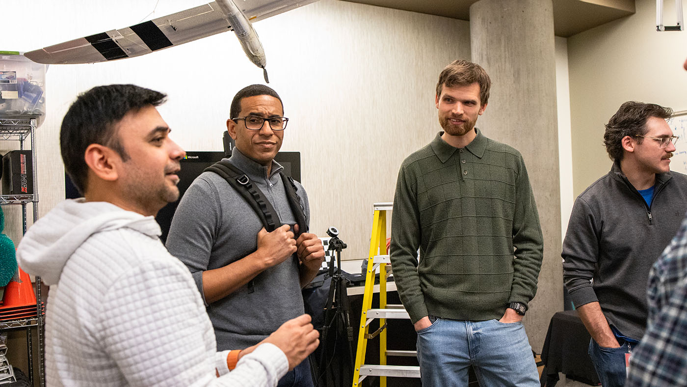 Ashley Llorens and three other men standing in a room