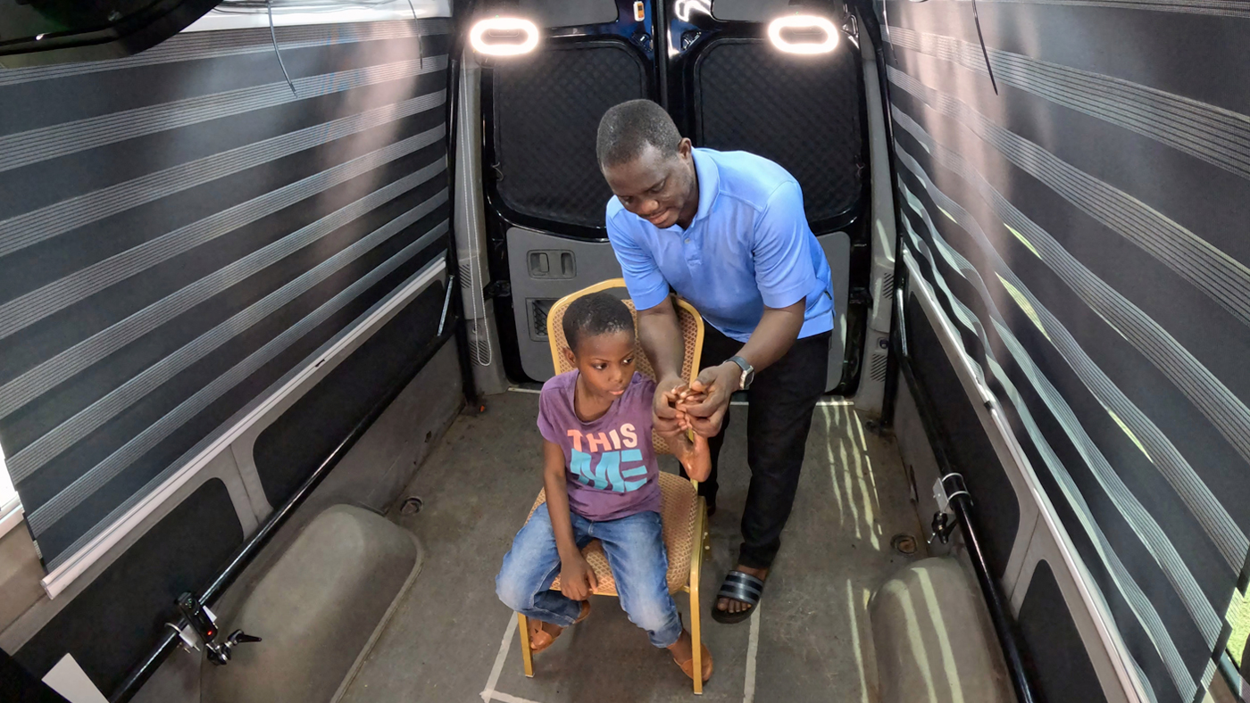 A father helps demonstrate the lack of movement in his child's hand to doctors who are viewing the live 3D Telemedicine session from around the world.