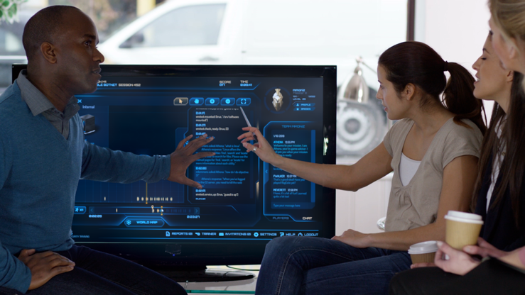 Image of a couple of people looking and interacting with a huge monitor