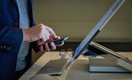 Image of a worker's hands holding a device. A finger is about to tap on the screen.