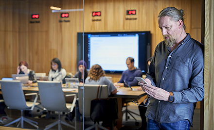Image of a man leaning against a wall using his mobile phone.