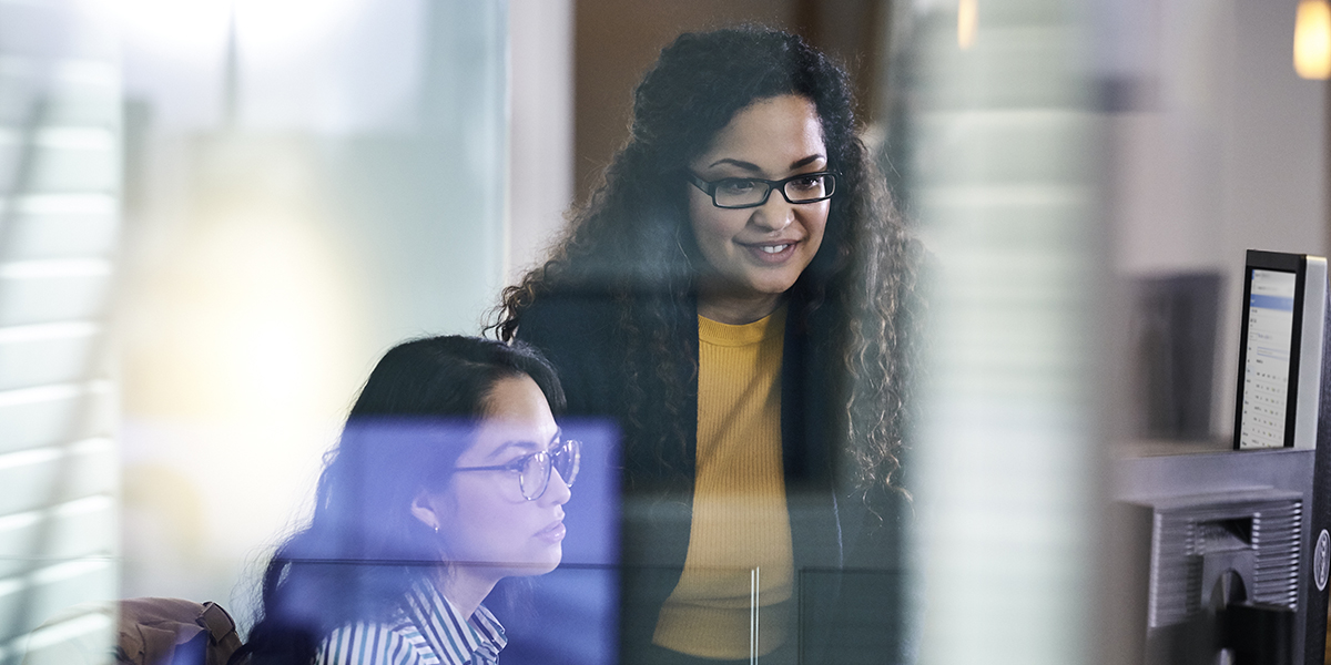 Two adult women working together at a computer.