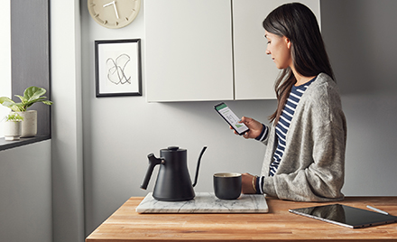 Image of a worker in a kitchen looking at her phone.