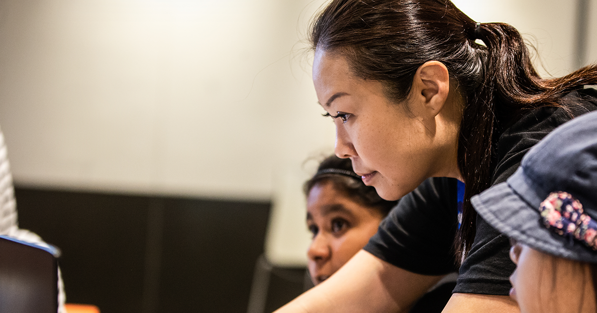 Image of a dev helping students in a classroom.