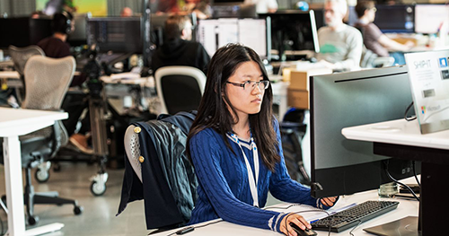 An image of a female developer working at her desk on her computer.
