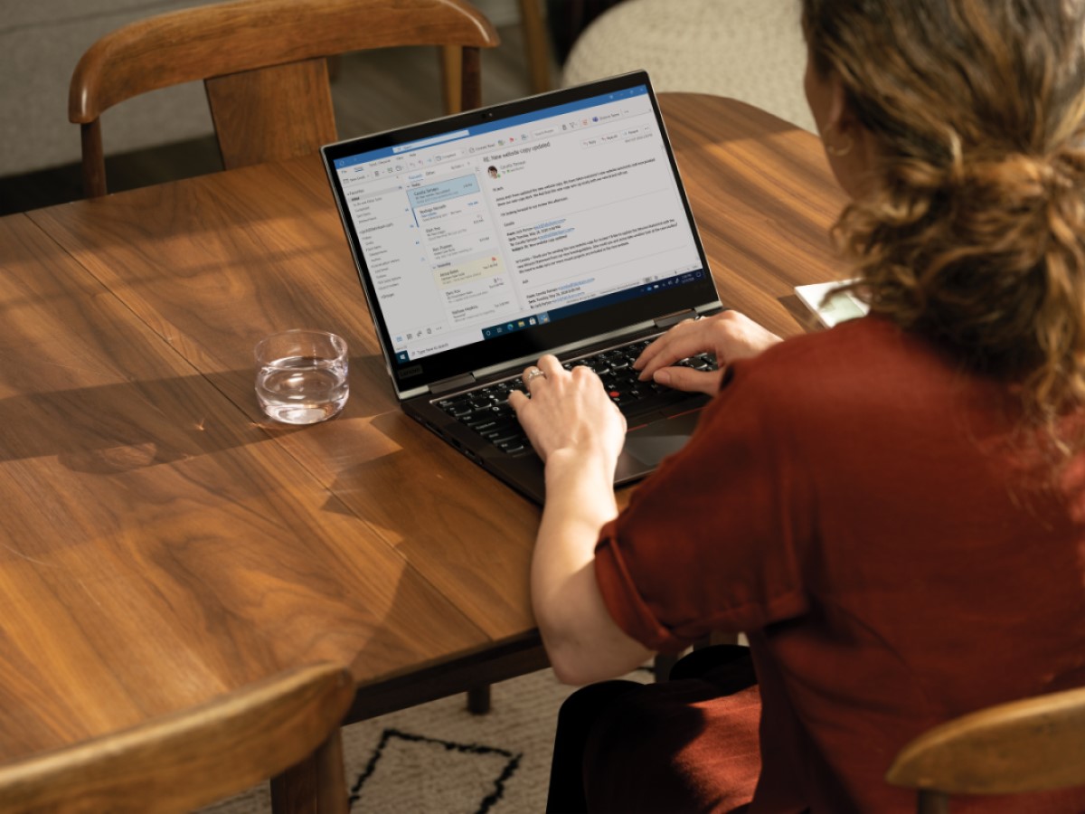 Over the shoulder photo at a dining room table with a Lenovo ThinkPad X1 Yoga. Remote Working collection.