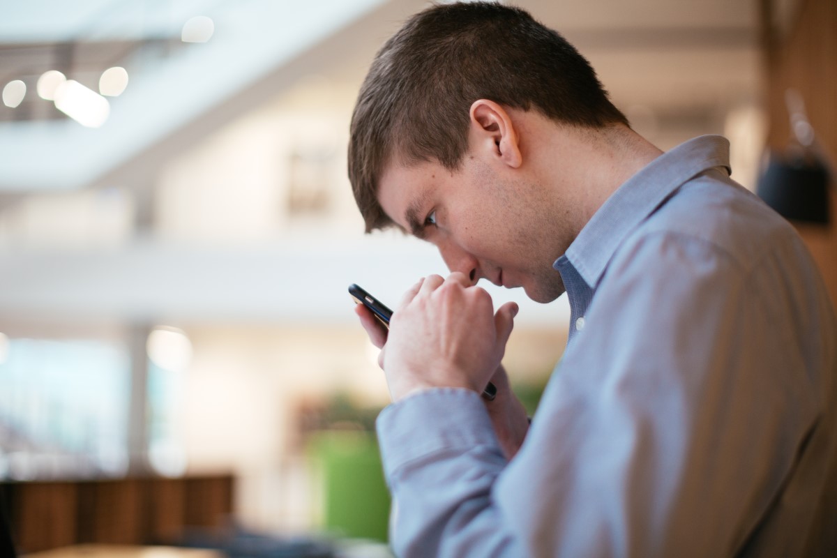 Man with low vision holds a mobile phone close to his face in order to view the screen.