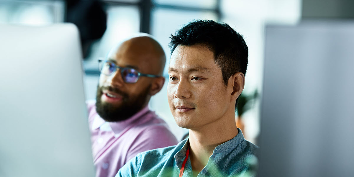 Two adult male IT professionals looking at a computer screen.