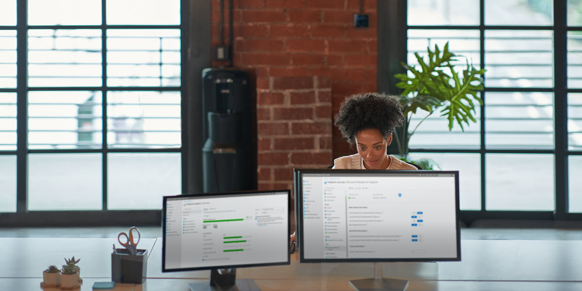 Individual at work behind two computer screens.