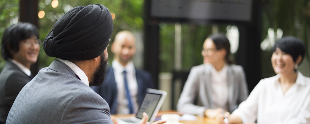 A group gathers around a table having a meeting in an office.