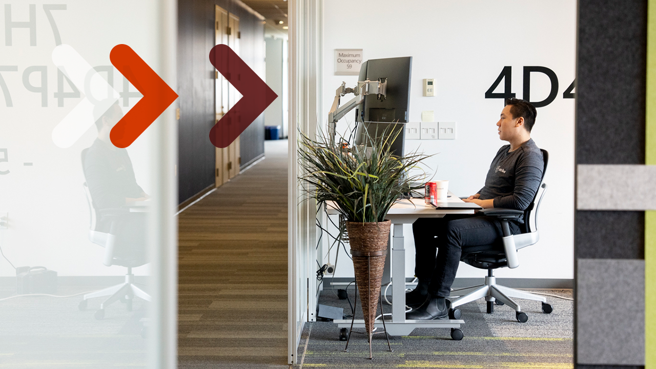 A man sits at a desk and works at a computer.