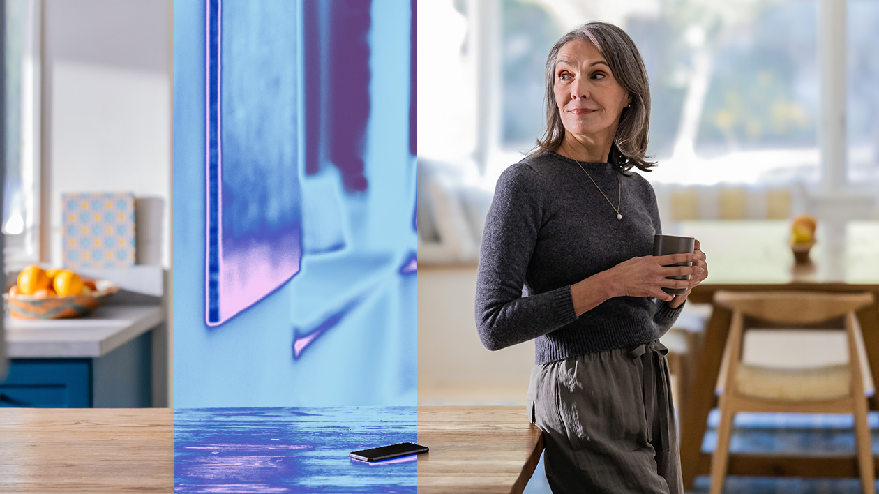 A woman holding a cup and standing near a table.