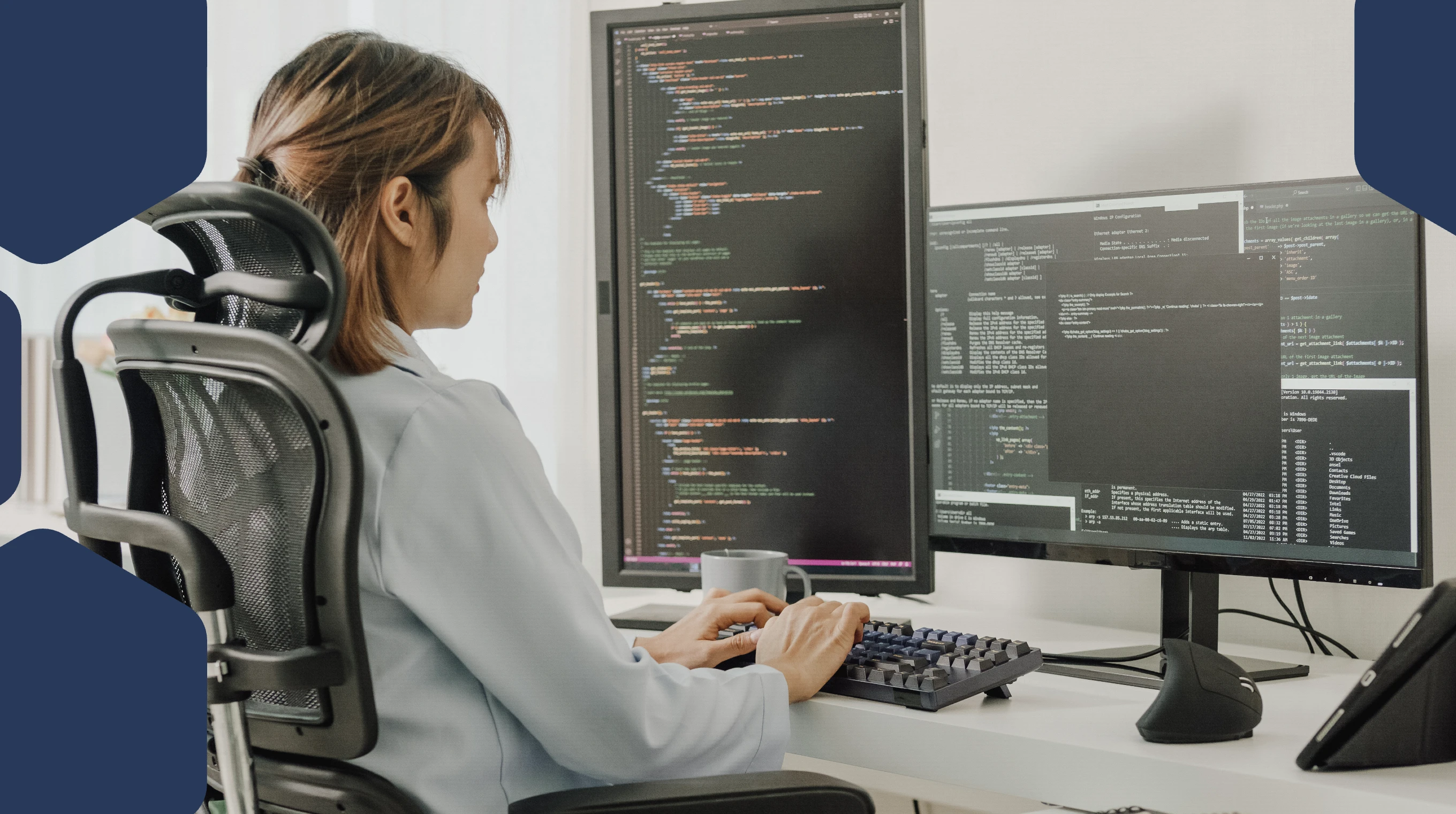 A woman sitting at a desk with a computer screen and a mug