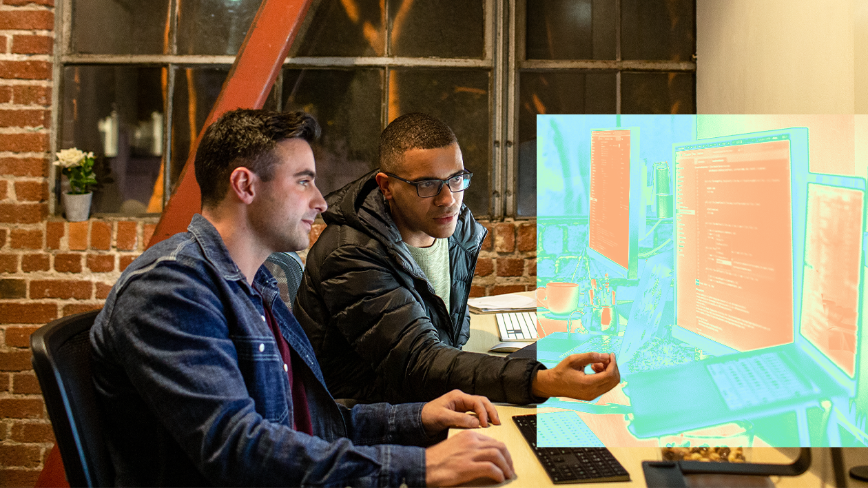 A group of men sitting at a table looking at a computer screen