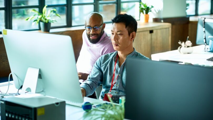 A group of men looking at a computer