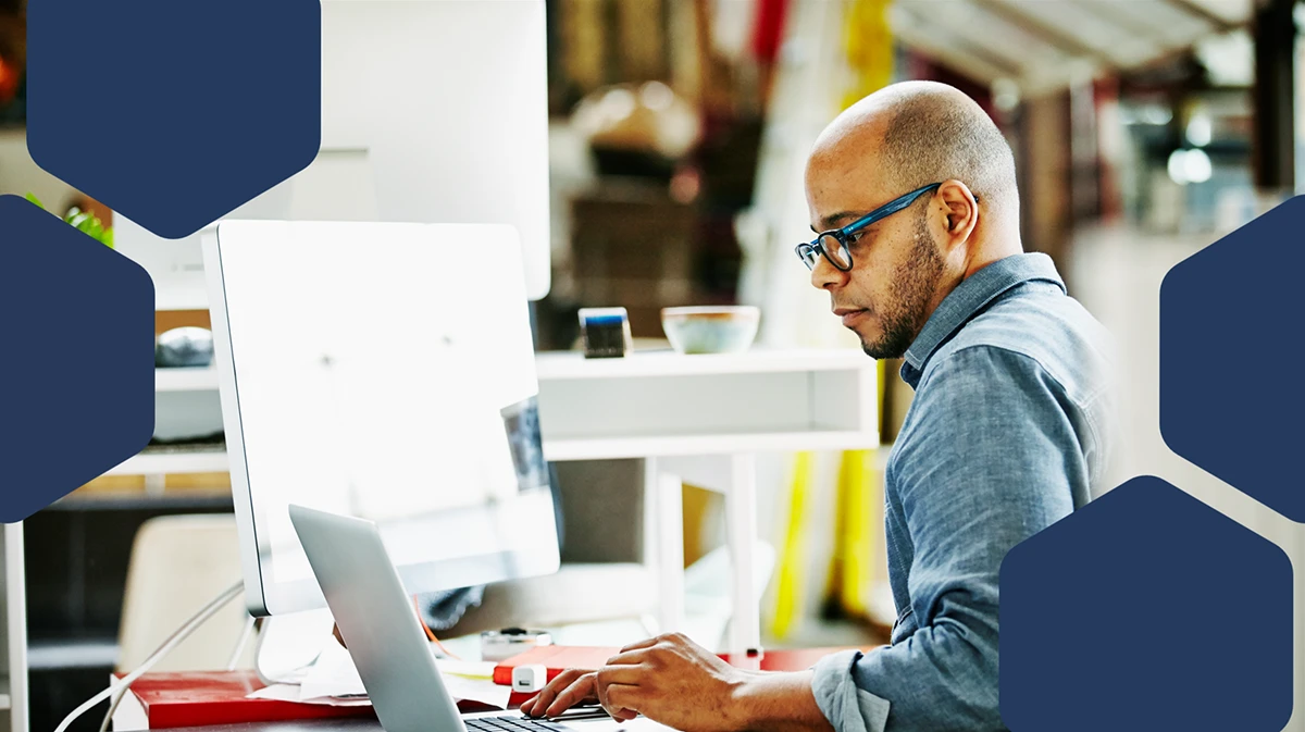 Photo of businessman sitting at workstation in startup office working on project on laptop