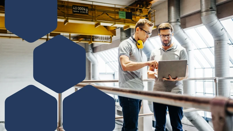 Photo of two engineers in a factory looking at laptop