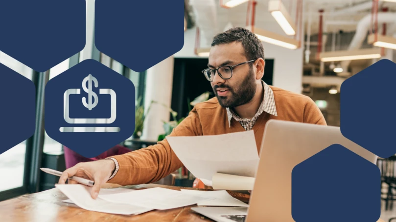 Professor works at a table in a campus office space