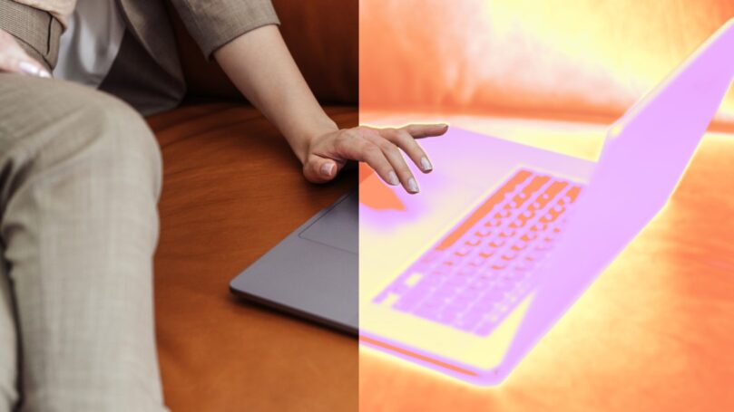 A person sitting on a couch touching a laptop.