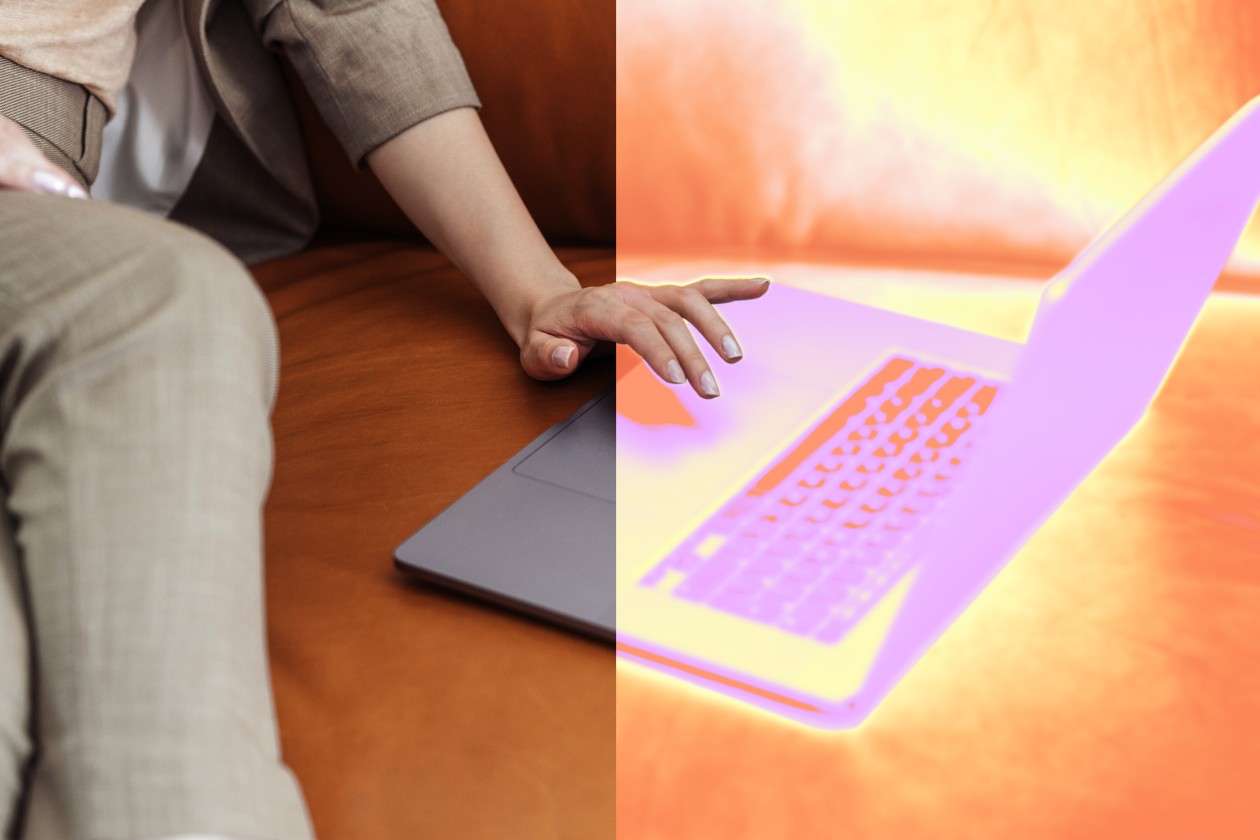 A person sitting on a couch touching a laptop.