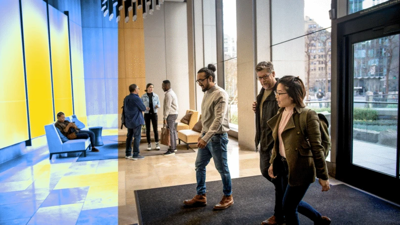 A group of people walking in the lobby of an office building.